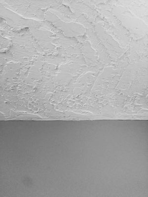 Tall skinny photo of a thick Hawk and Trowel Drywall texture on the ceiling with smooth walls