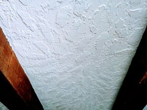 Picture of a hawk and trowel drywall texture next to large wooden beams applied with thick drywall compound