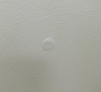 Picture of a loose screw in drywall causing the paint to crack