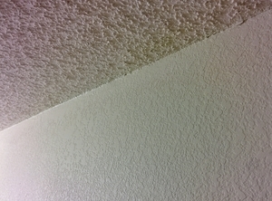 Angled photo of popcorn texture on the ceiling and knockdown on the walls