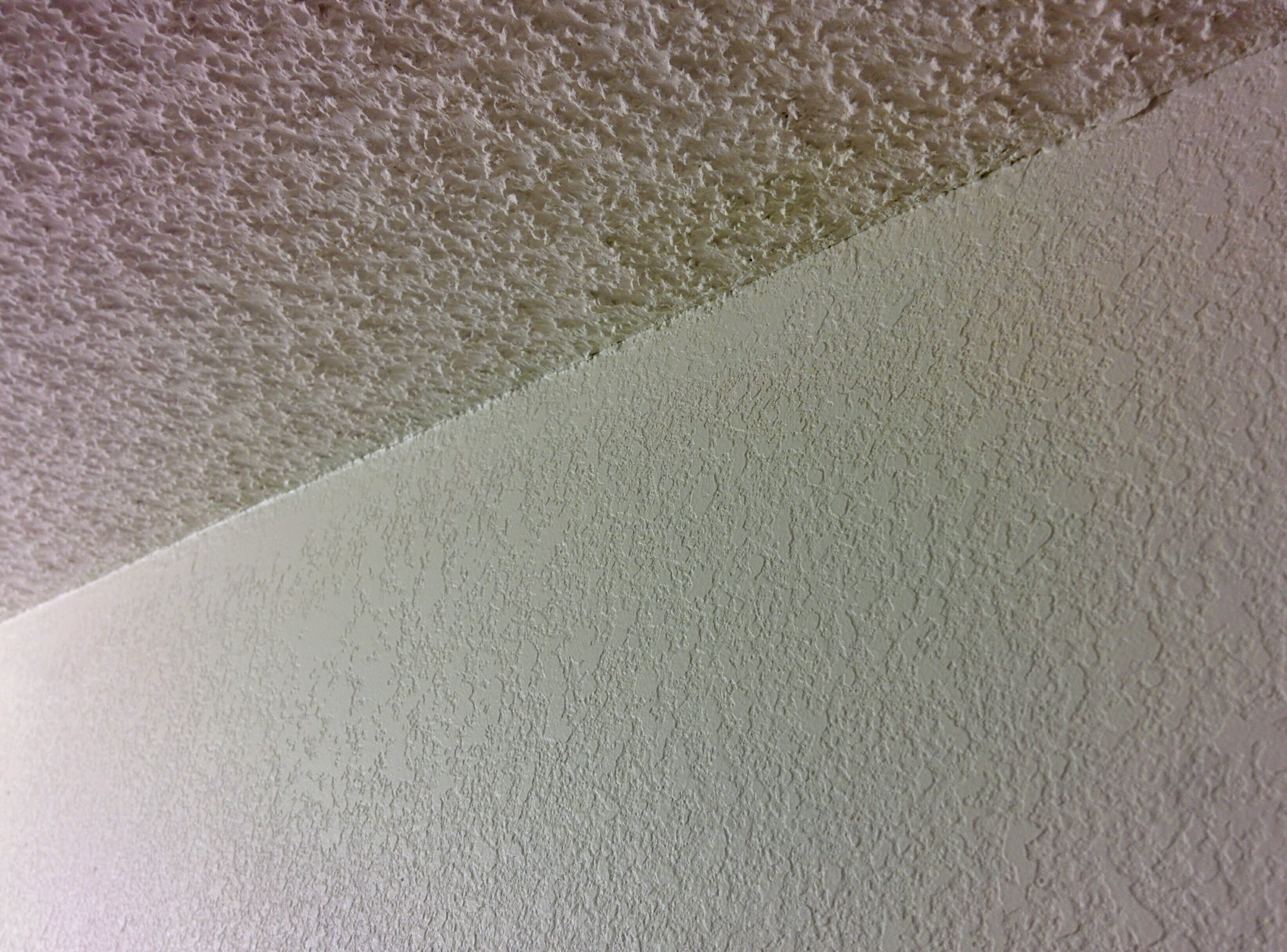 Gekantelde foto van popcorntextuur op het plafond en knockdown op de muren
