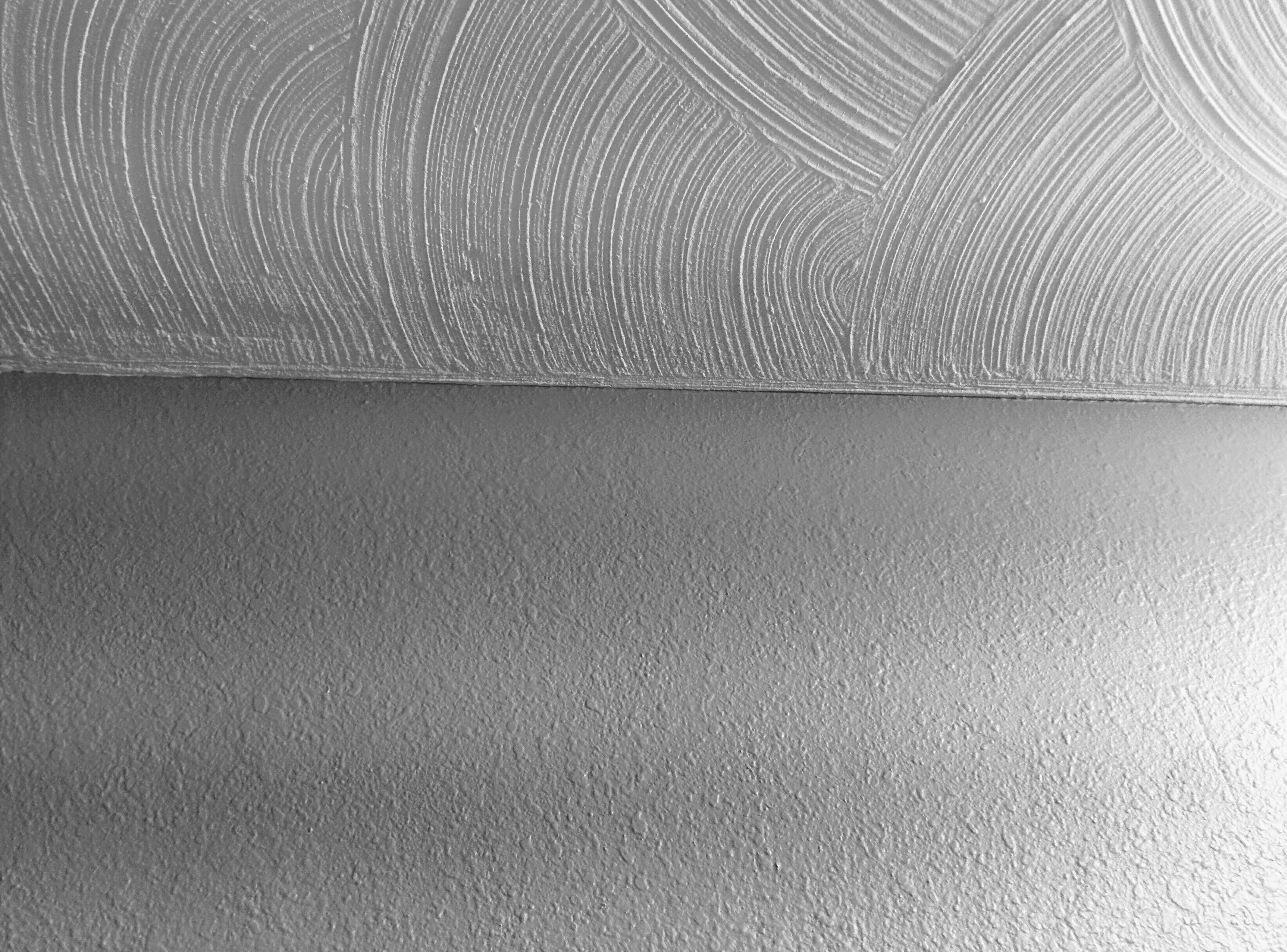Photo de la texture tourbillonnante de cloison sèche au plafond et de la texture knockdown sur le mur